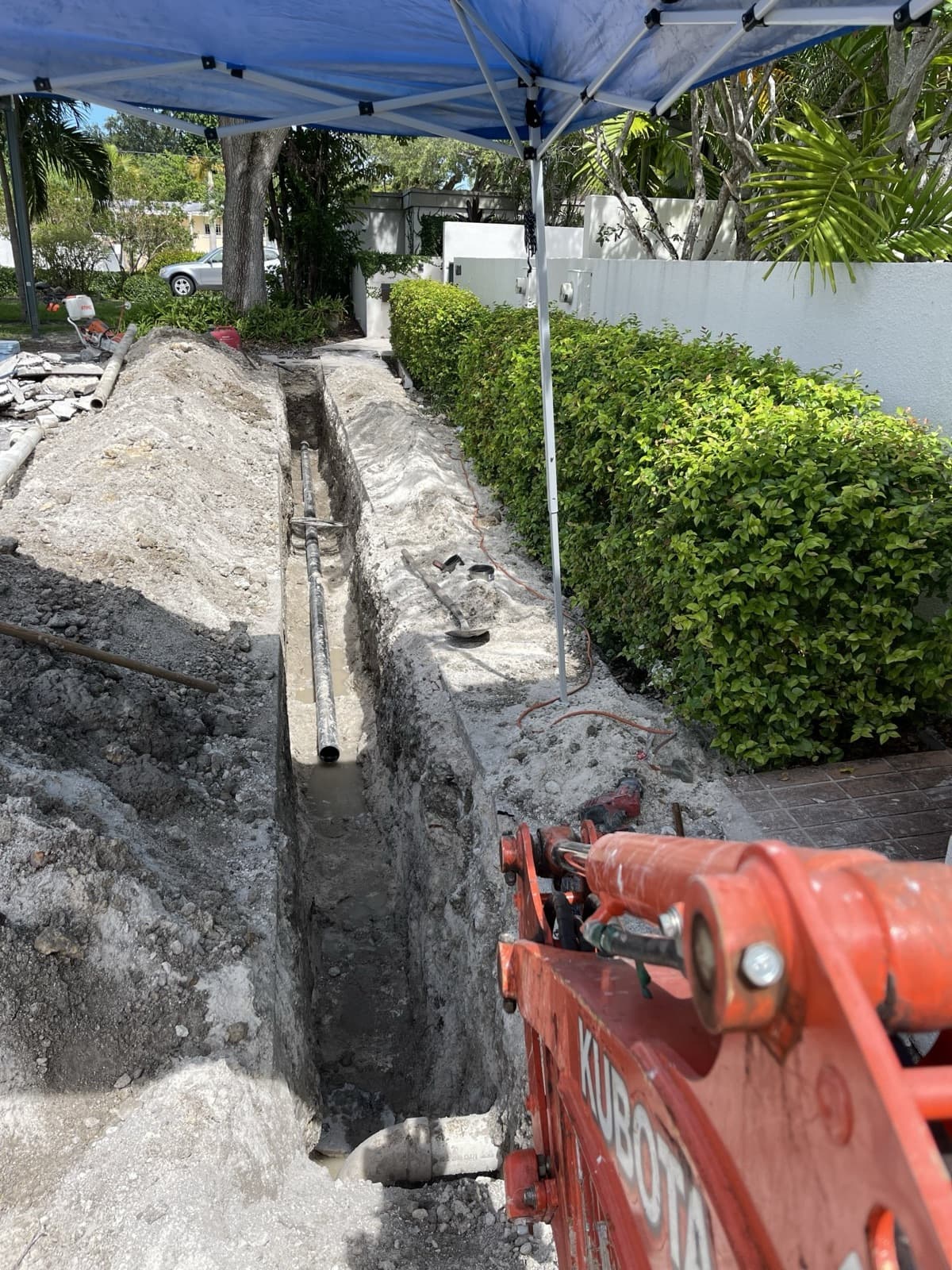 Zanja abierta en un patio, con el brazo de la excavadora