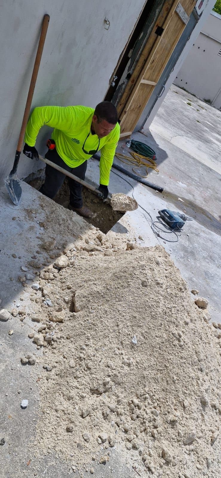Plomero de RCR excavando junto a un muro para llegar a la tubería