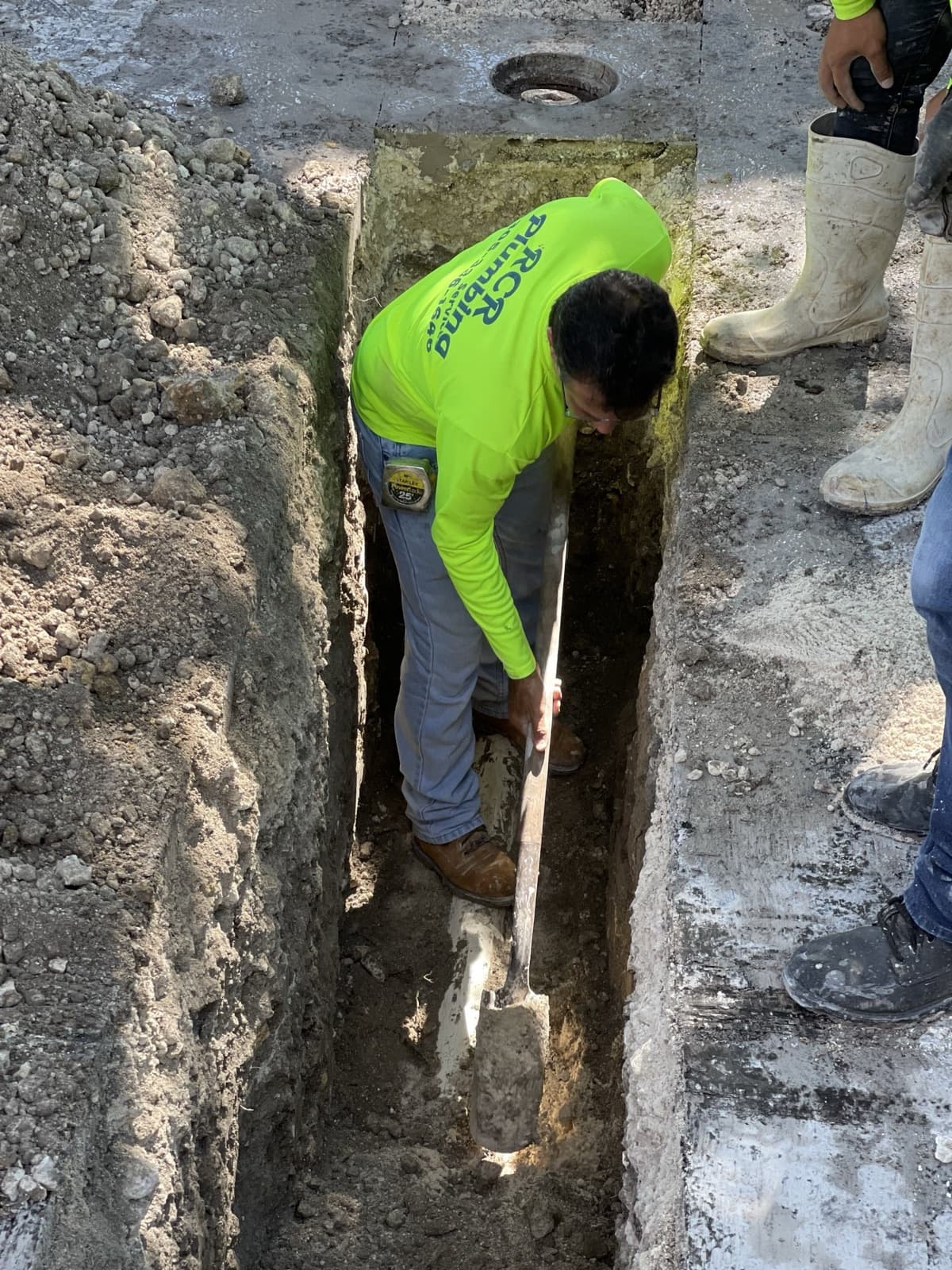 Plomero de RCR trabajando dentro de una zanja en el patio de una casa
