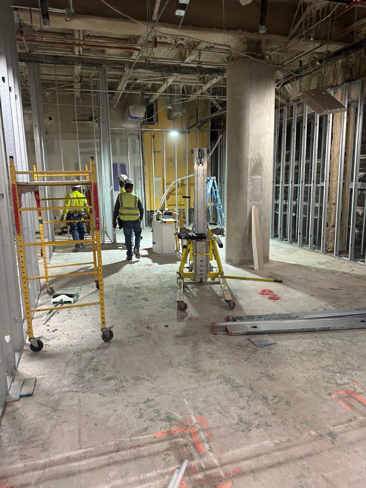 Plomeros de RCR con andamio amarillo en un interior en obra del aeropuerto