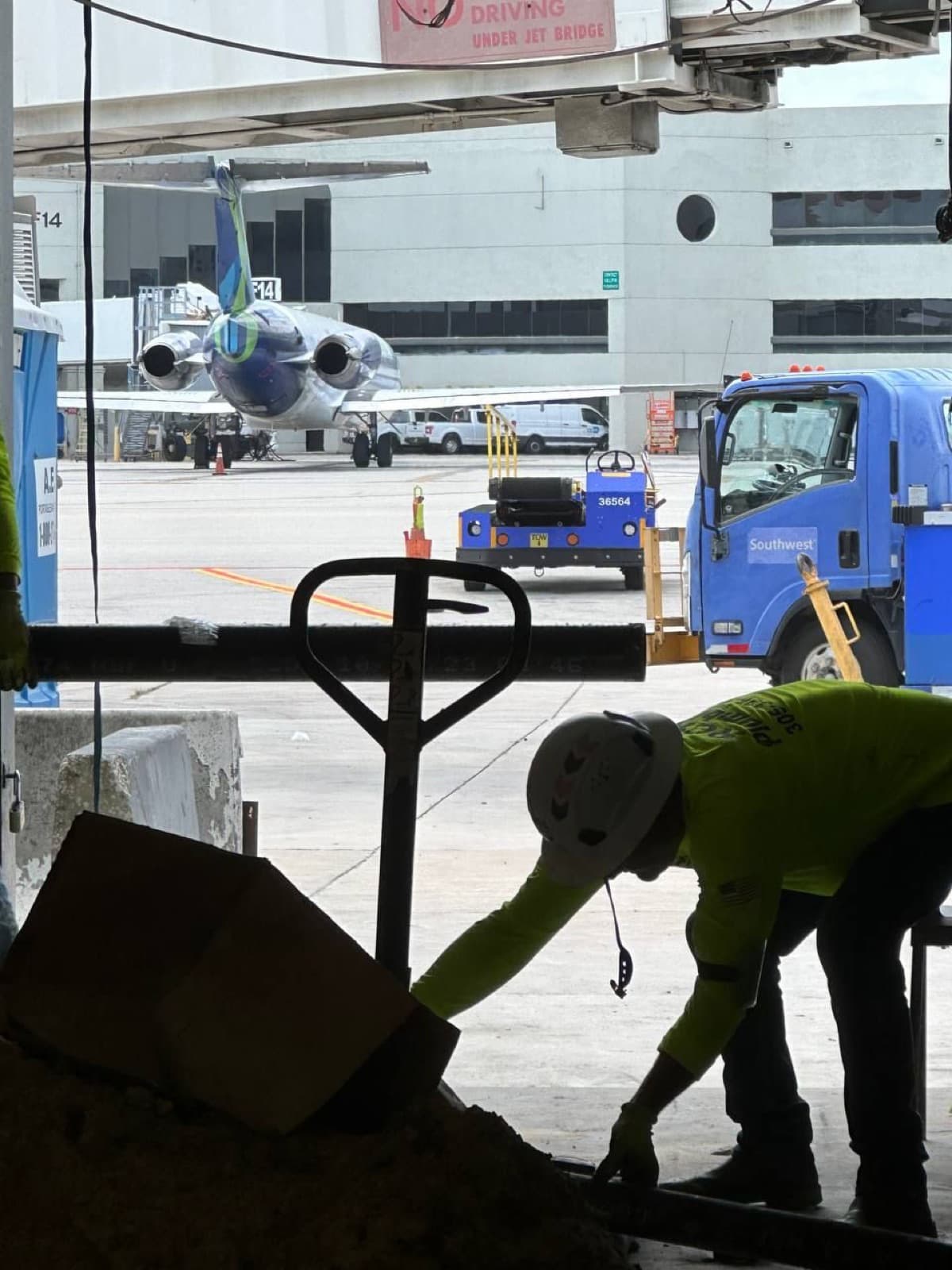 Plomero de RCR moviendo material en la plataforma, con un avión detrás
